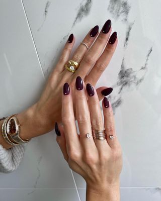 Dark red long almond nails with gemstones