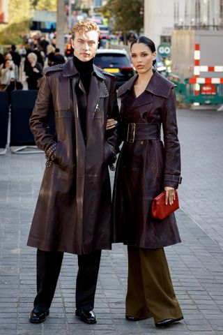 Lucky Blue Smith and Nara Smith wear burgundy leather trench coats, pants, and black shoes.