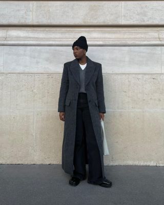 @thevisuelofgrace wearing a beanie, gray coat, gray sweater, white t-shirt, and black trousers.