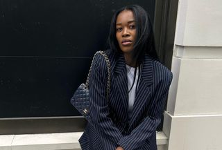 @nlmarilyn wearing a navy blue pinstripe suit with a navy blue Chanel quilted Flap Bag.