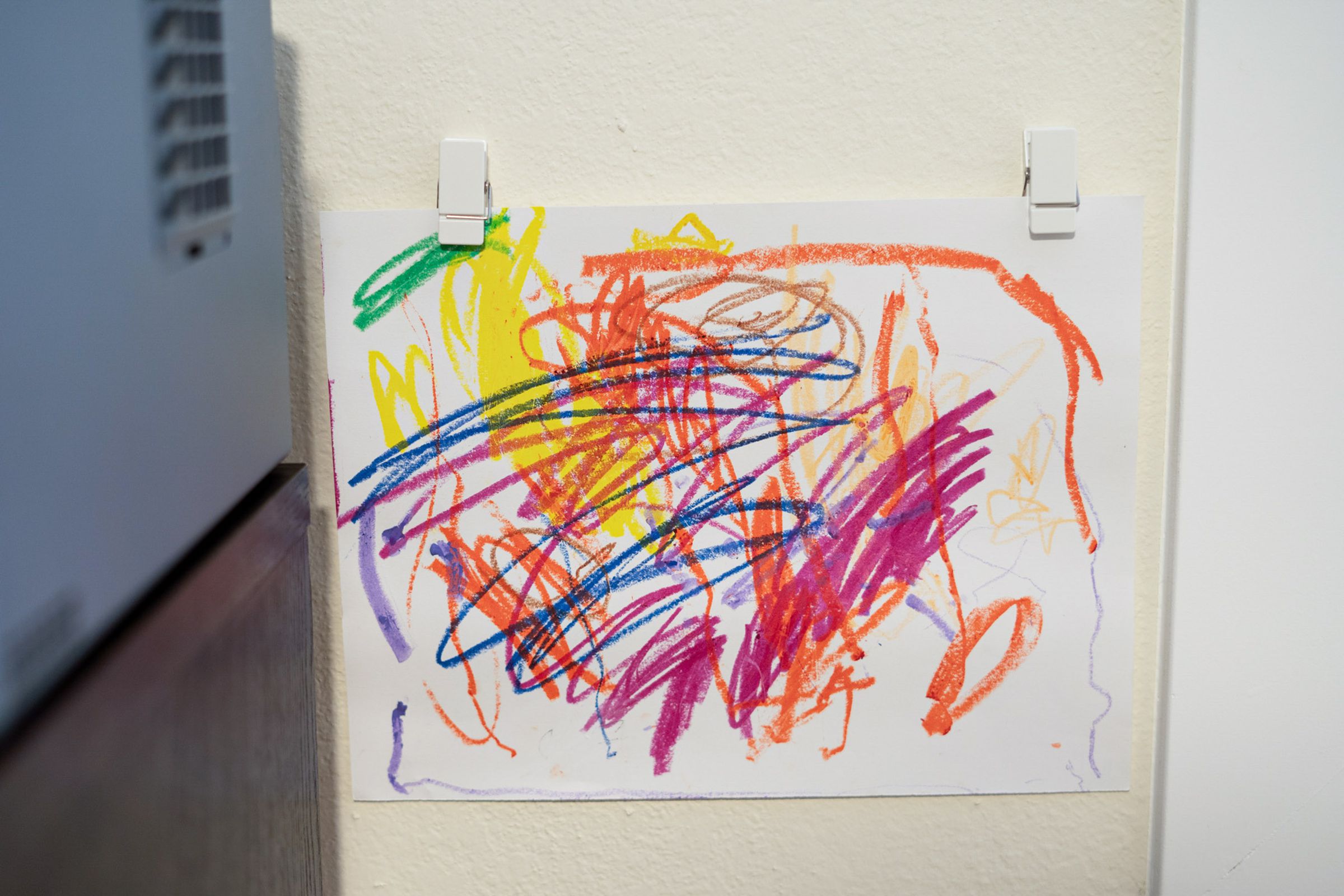 A child’s drawing held up by two white clips.