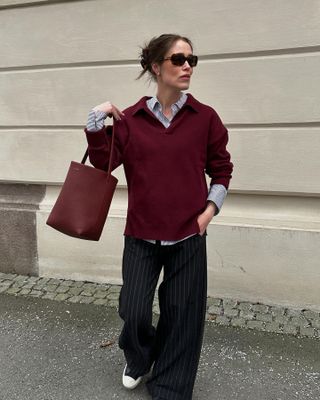 Woman wearing an elegant burgundy sweater and pinstripe pants.