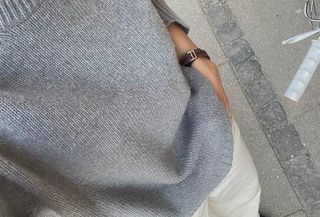 Woman wearing a gray crewneck sweater.