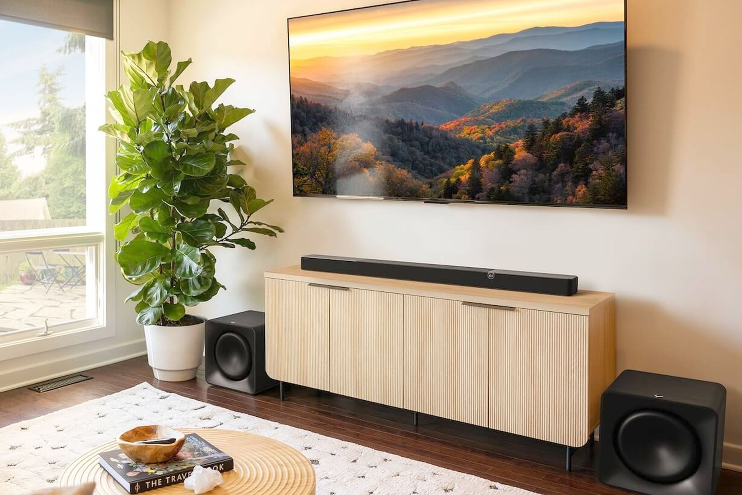 The Klipsch Flexus Core 300 soundbar sitting on a wooden cabinet beneath a wall-mounted TV.