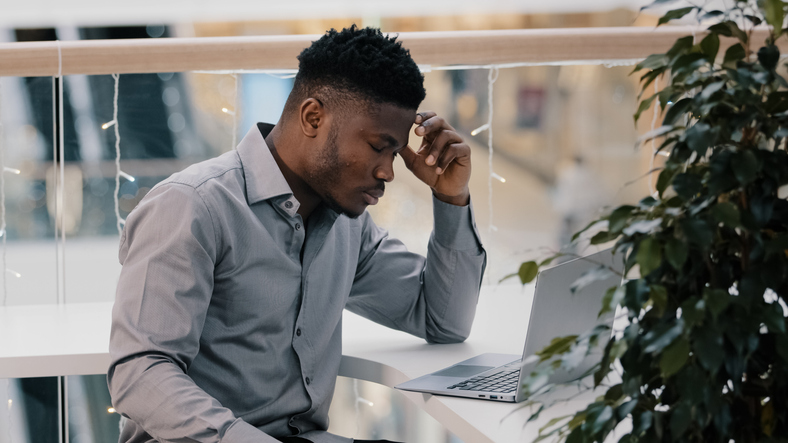 Shocked young businessman working on laptop feeling frustrated stressed by problem despair unsuccessful results unsaved information loss of network connection checking email reading bad news worried