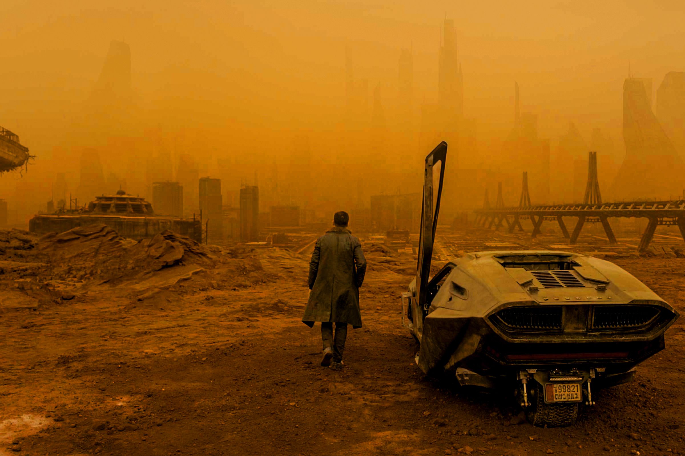 A man walking away from a car and into the smoky ruins of an apocalyptic city.