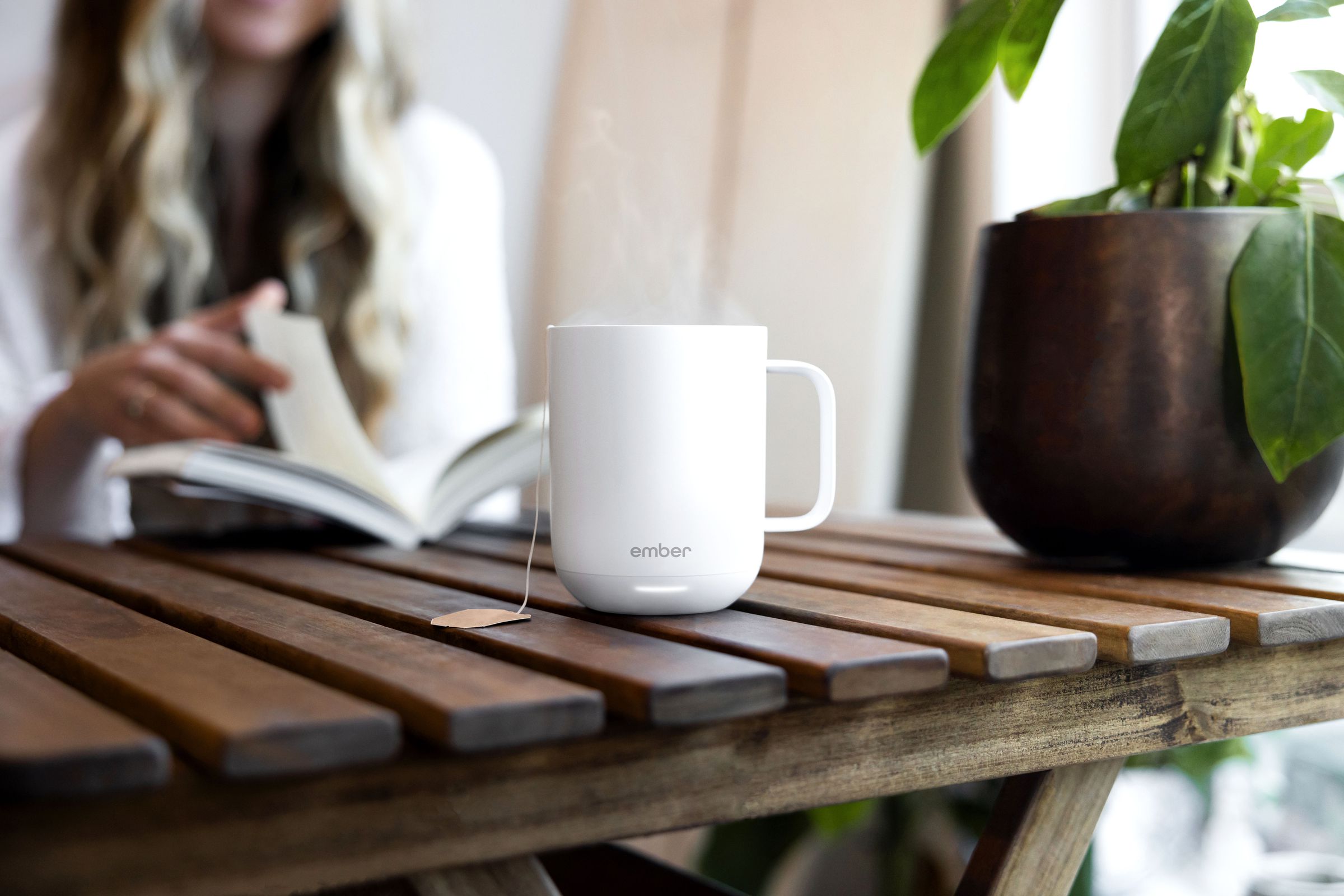 An Ember Mug 2 self-heating smart mug sitting on a table, filled with hot tea.