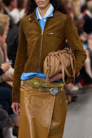 A close-up imagine of a brown suede zip-up jacket at the Miu Miu spring summer 2025 runway show in Paris.