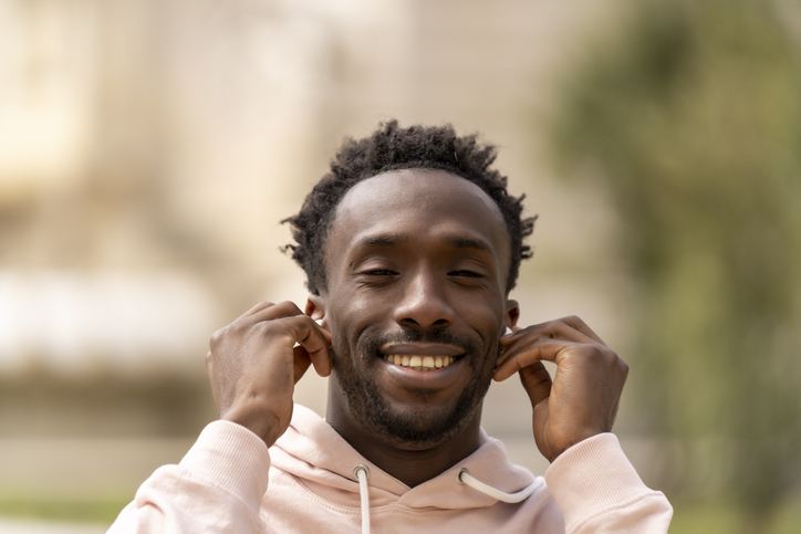 The man smiles as he adjusts his earbuds, enjoying the music.