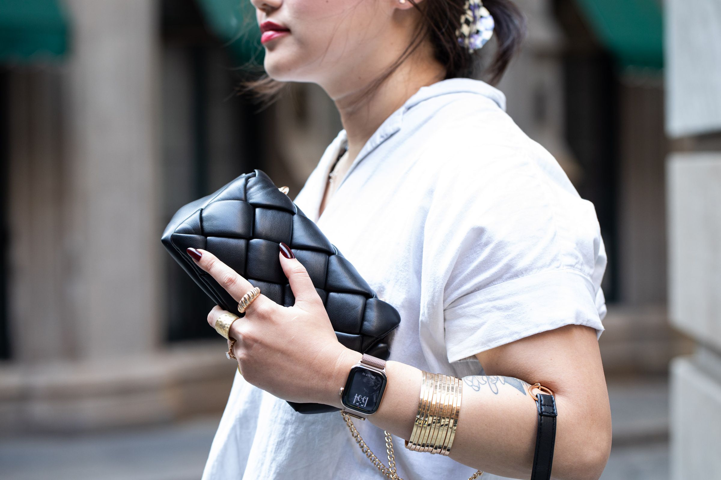 Person wearing gold Apple Watch Series 10 in titanium while wearing lots of matching accessories.