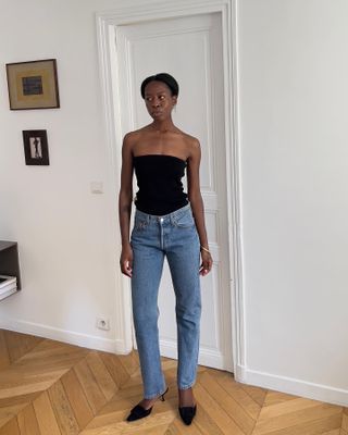 Sylvie Mus wearing a black tube top and Levi's 501 jeans with black heels.