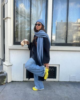 Winter trainer outfits: @amaka.hamelijnck wears a black coat with wide jeans and trainers