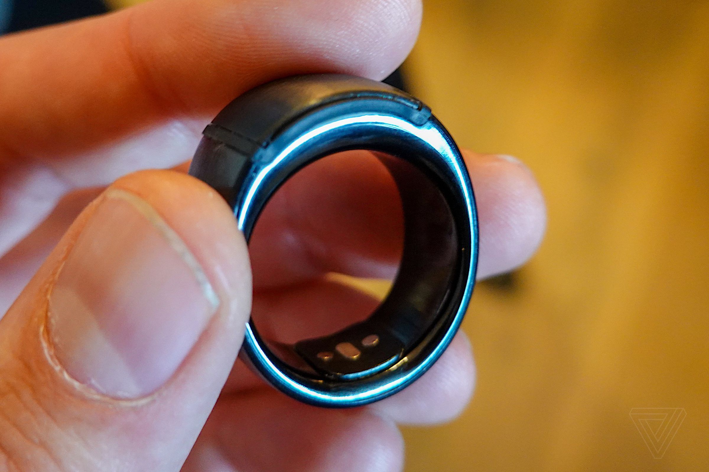 A close-up of the Amazon Echo Loop smart ring held between three fingers.