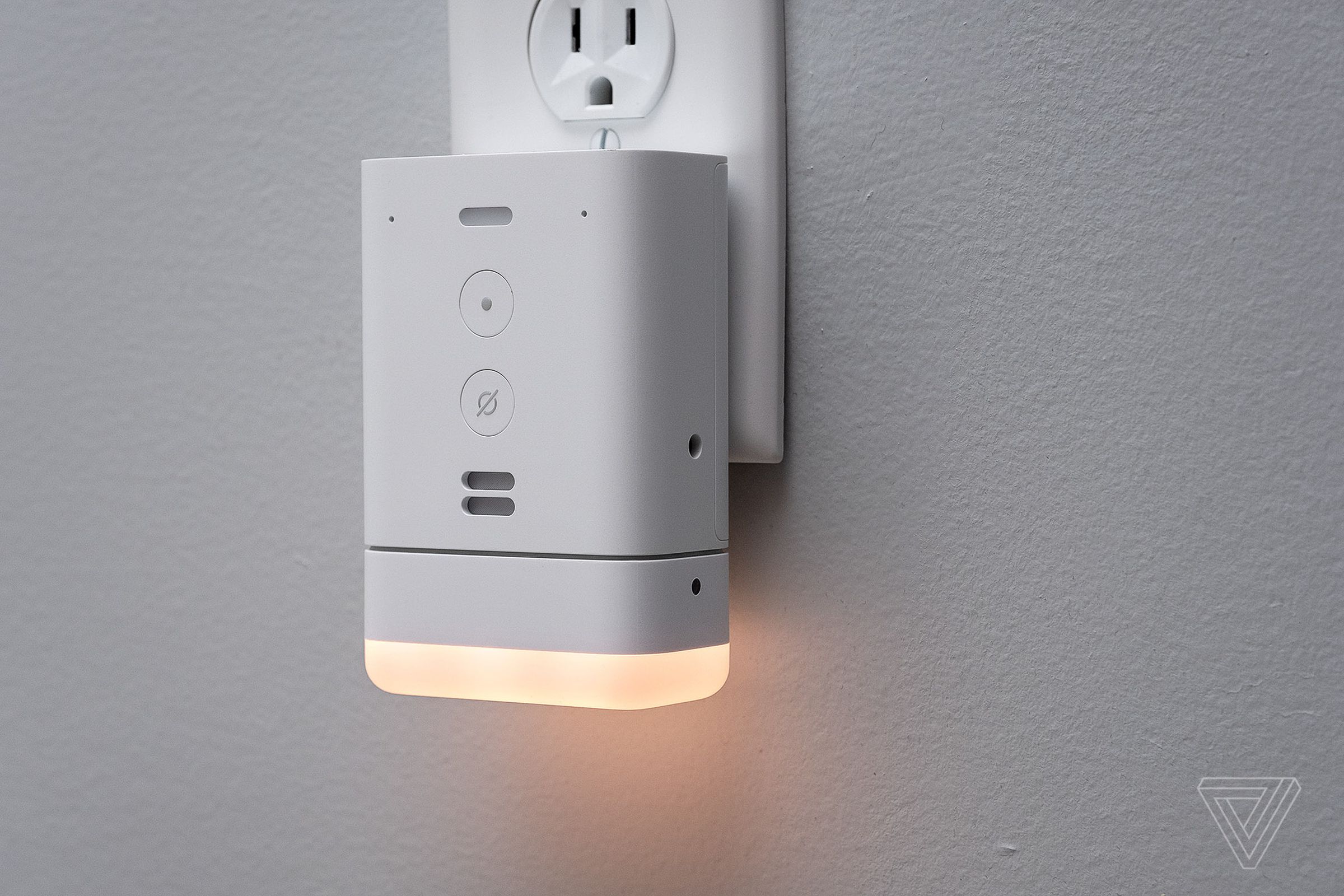 The Amazon Echo Flex connected to a wall outlet while casting a warm glow below it.