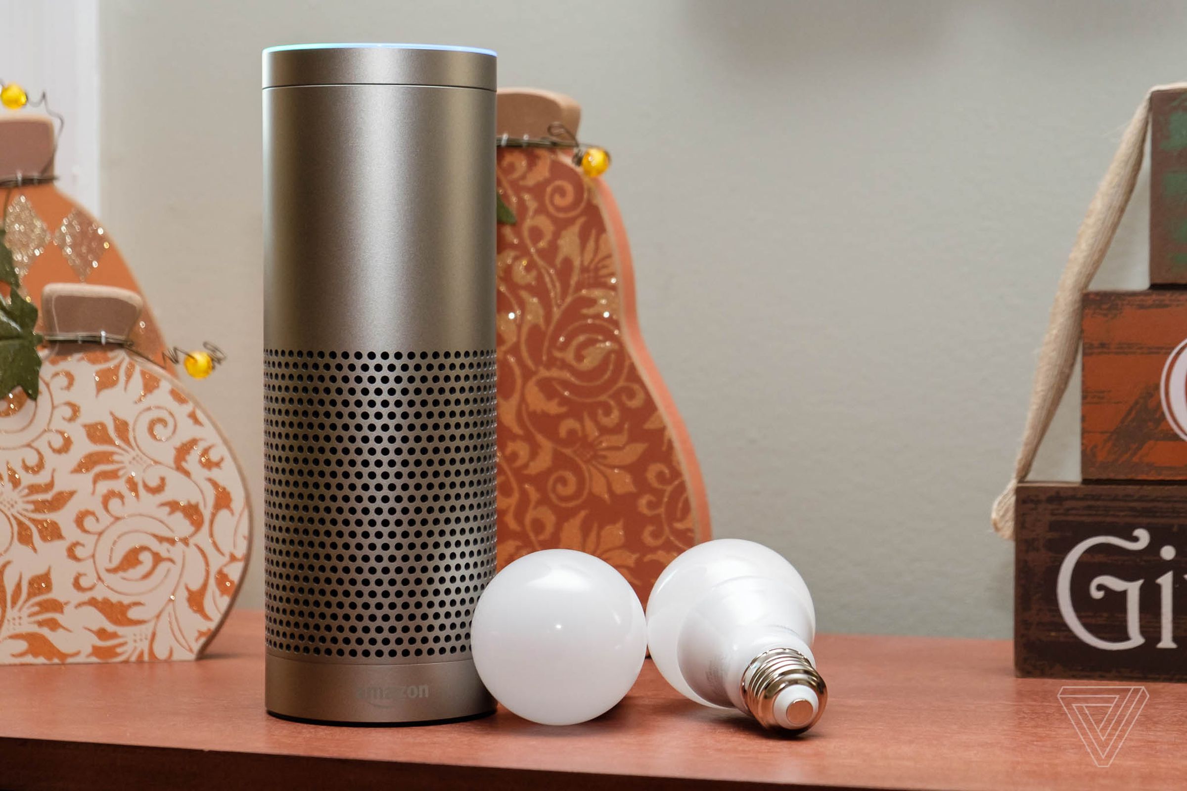 The Amazon Echo Plus smart speaker on a desk next to two smart light bulbs.