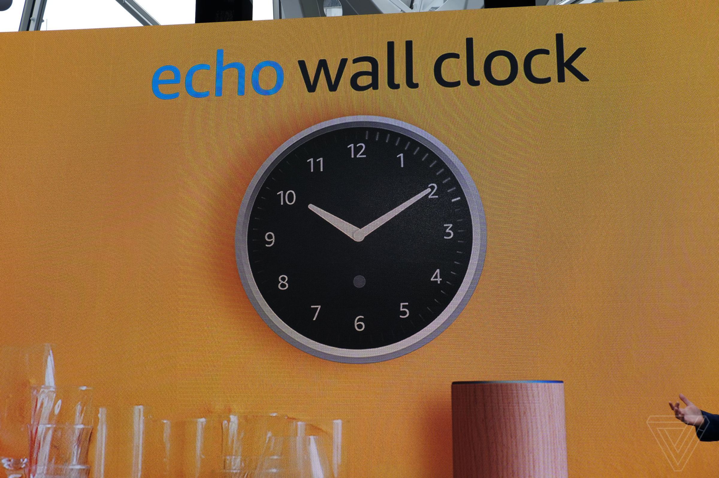 A photo of a large screen showing the Amazon Echo Wall Clock on an orange wall in a kitchen setting.