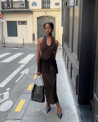 Woman wears brown knit dress and black bag