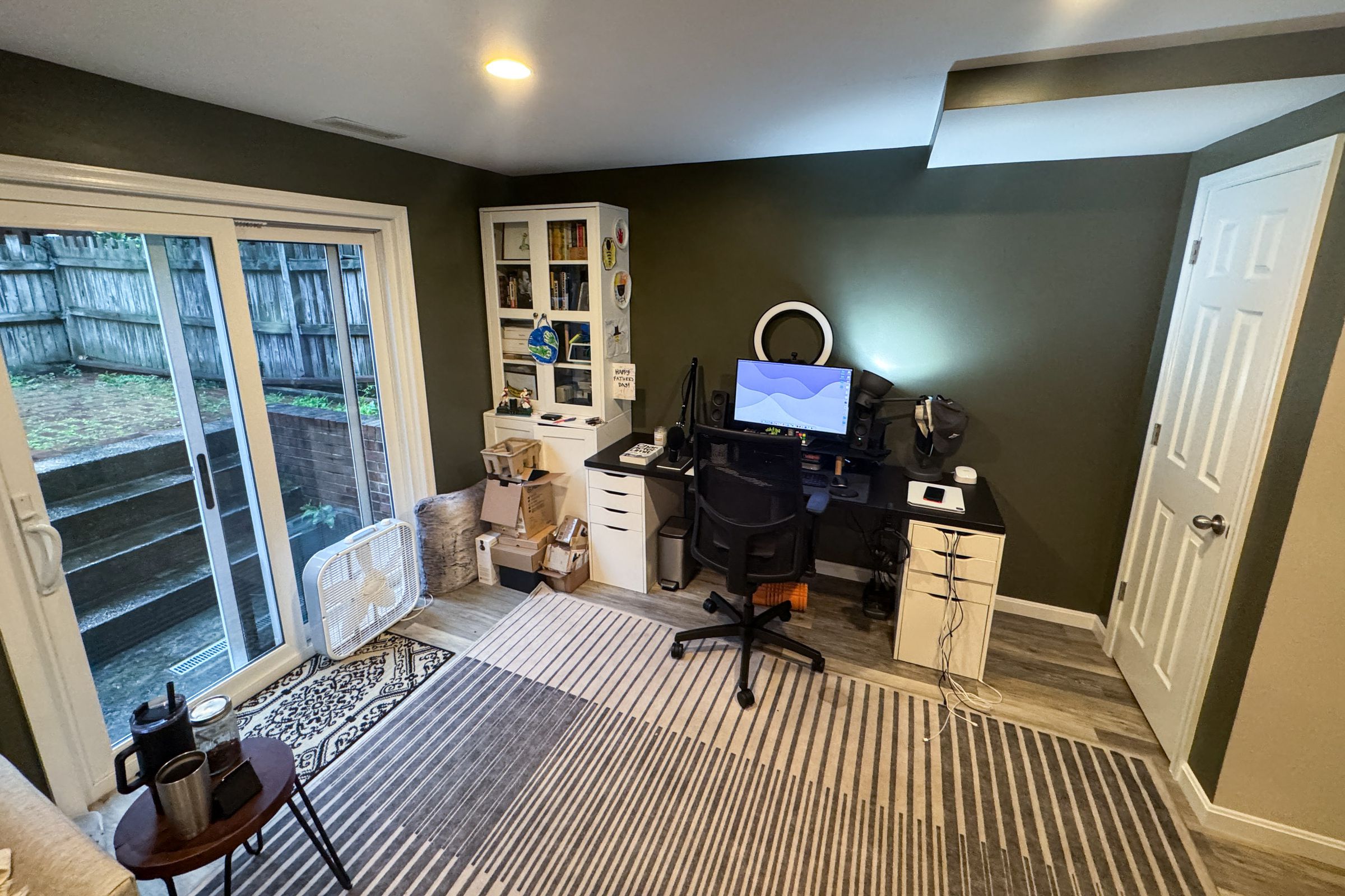 Basement office with desk, bookcase, sliding doors leading to a back garden.