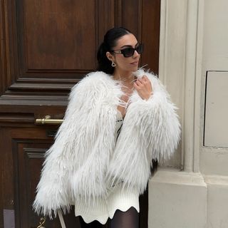 Woman wearing a fluffy white coat and sunglasses