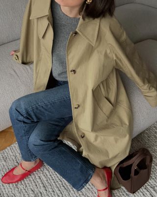 Woman wears red mary jane shoes with jeans and a beige jacket