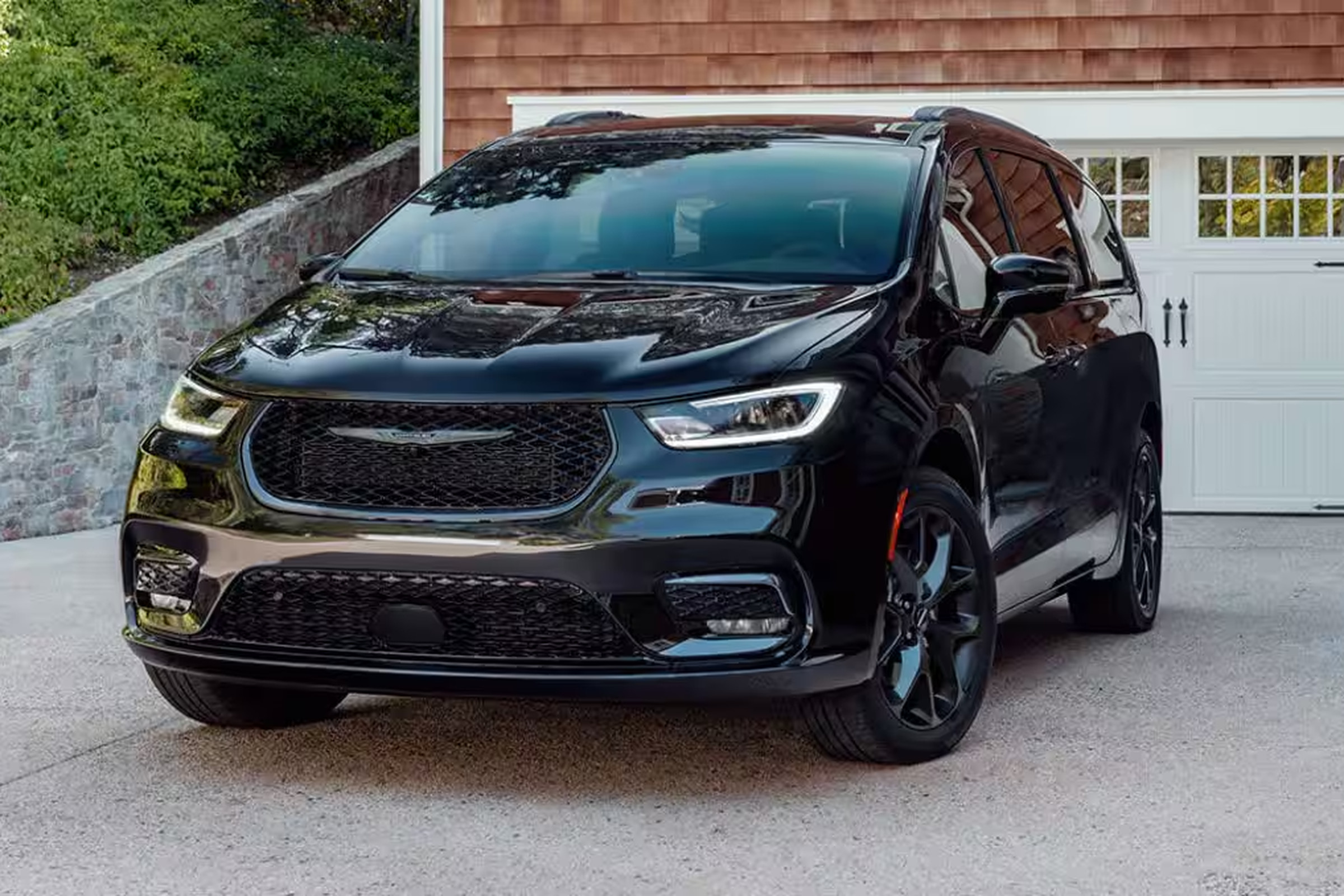 A 2024 Chrysler Pacifica in dark blue, sitting in a driveway. Three-quarter view of the vehicle, taken from the front.