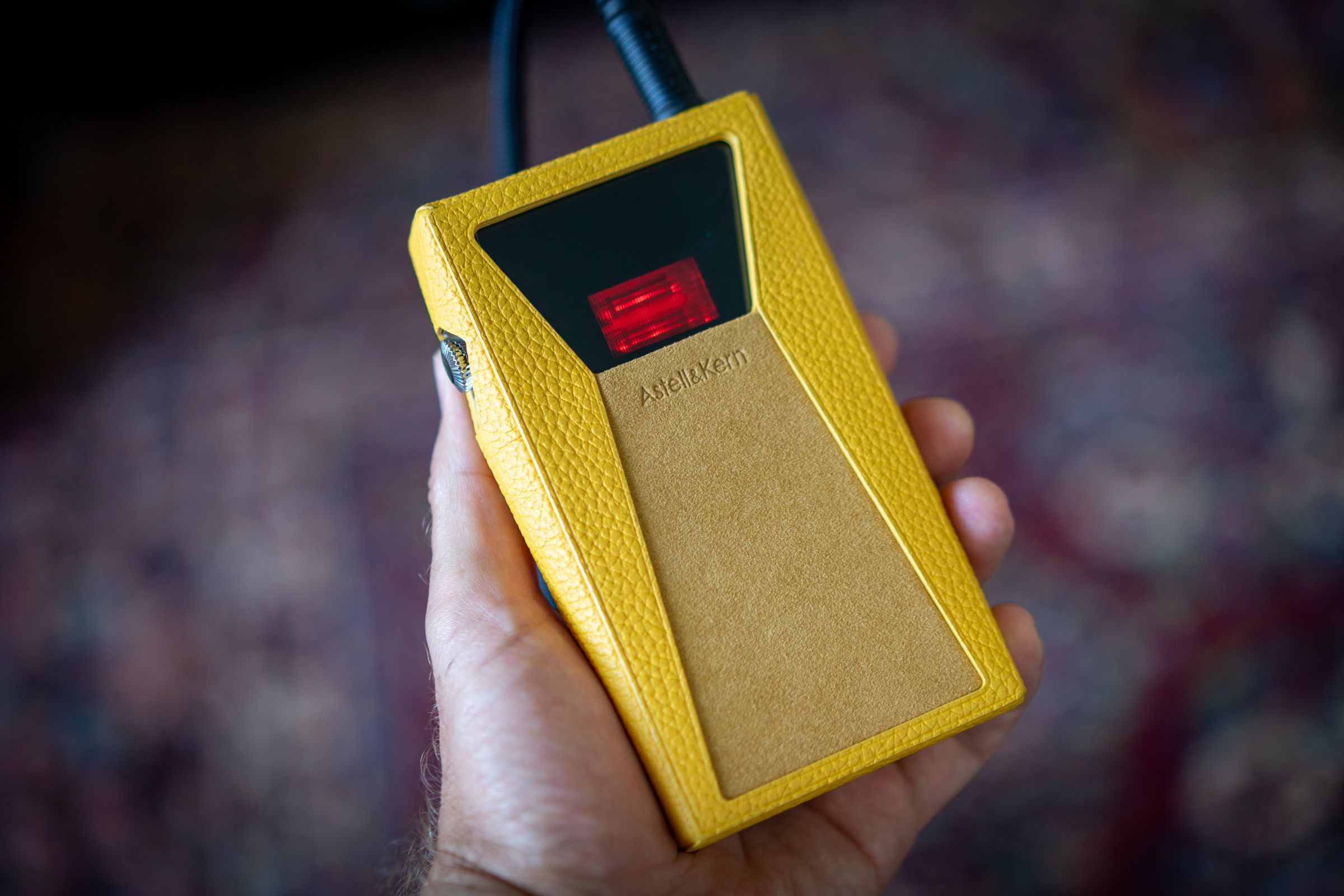 Image of Astell &amp; Kern SP3000T media player, an angular portable media player with silver edges and a red tube amp on the back. Some images show a yellow calfskin leather case.