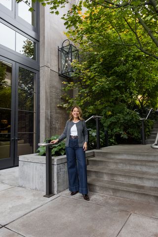 Sandy Koszarek wearing a gray crewneck cardigan, white tee, and wide-leg jeans.