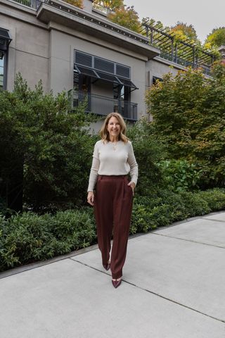 Sandy Koszarek wearing a white long-sleeve, burgundy trousers, and pointed toe heels.