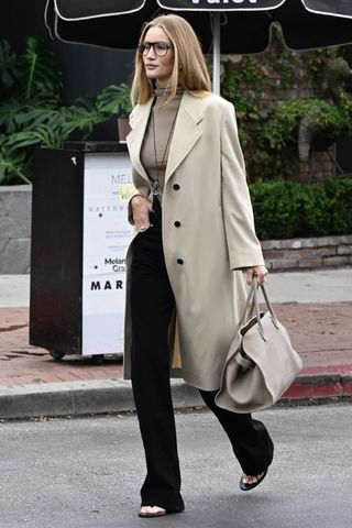 Rosie Huntington-Whiteley carrying a taupe bag with a matching coat and black trousers.