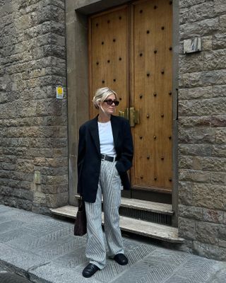  @lucywilliams02 wearing a black blazer, white T-shirt, and striped cargo pants.