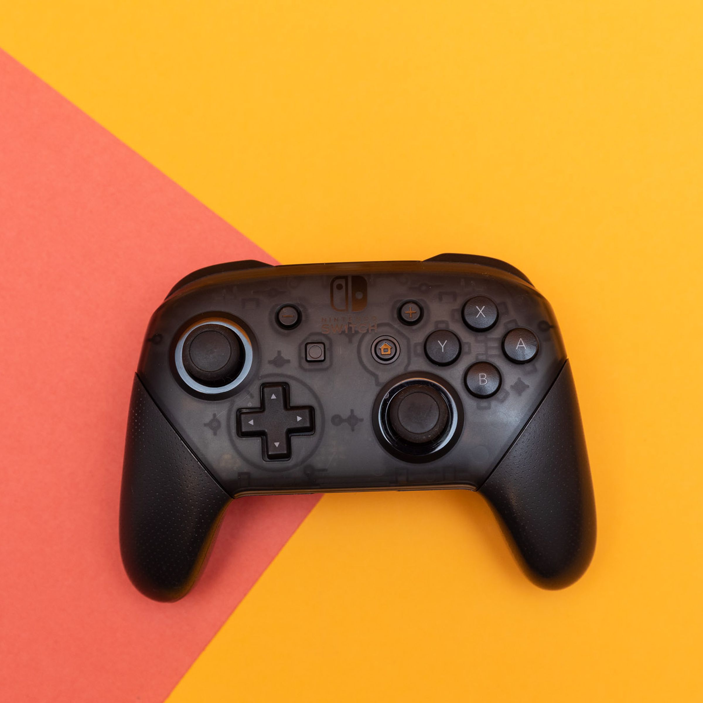 The Nintendo Switch Pro Controller sitting flat on a two-colored backdrop.