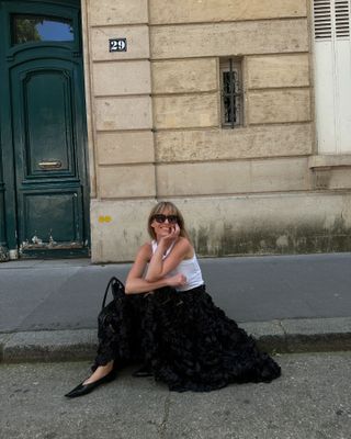 Influencer wearing a white tank top, black full skirt, and pointed-toe flats