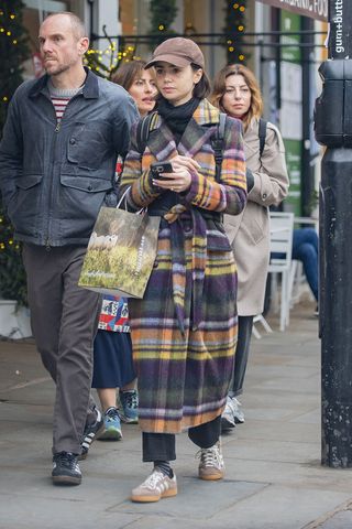 Lily Collins wearing a plaid coat and tan Adidas sneakers