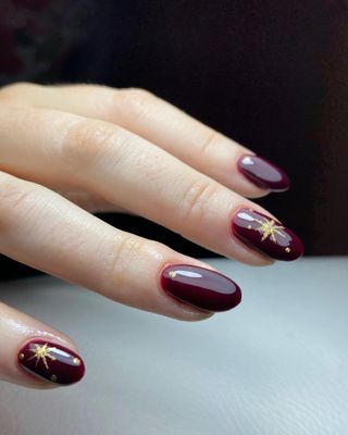 Burgundy nails with gold star nail art