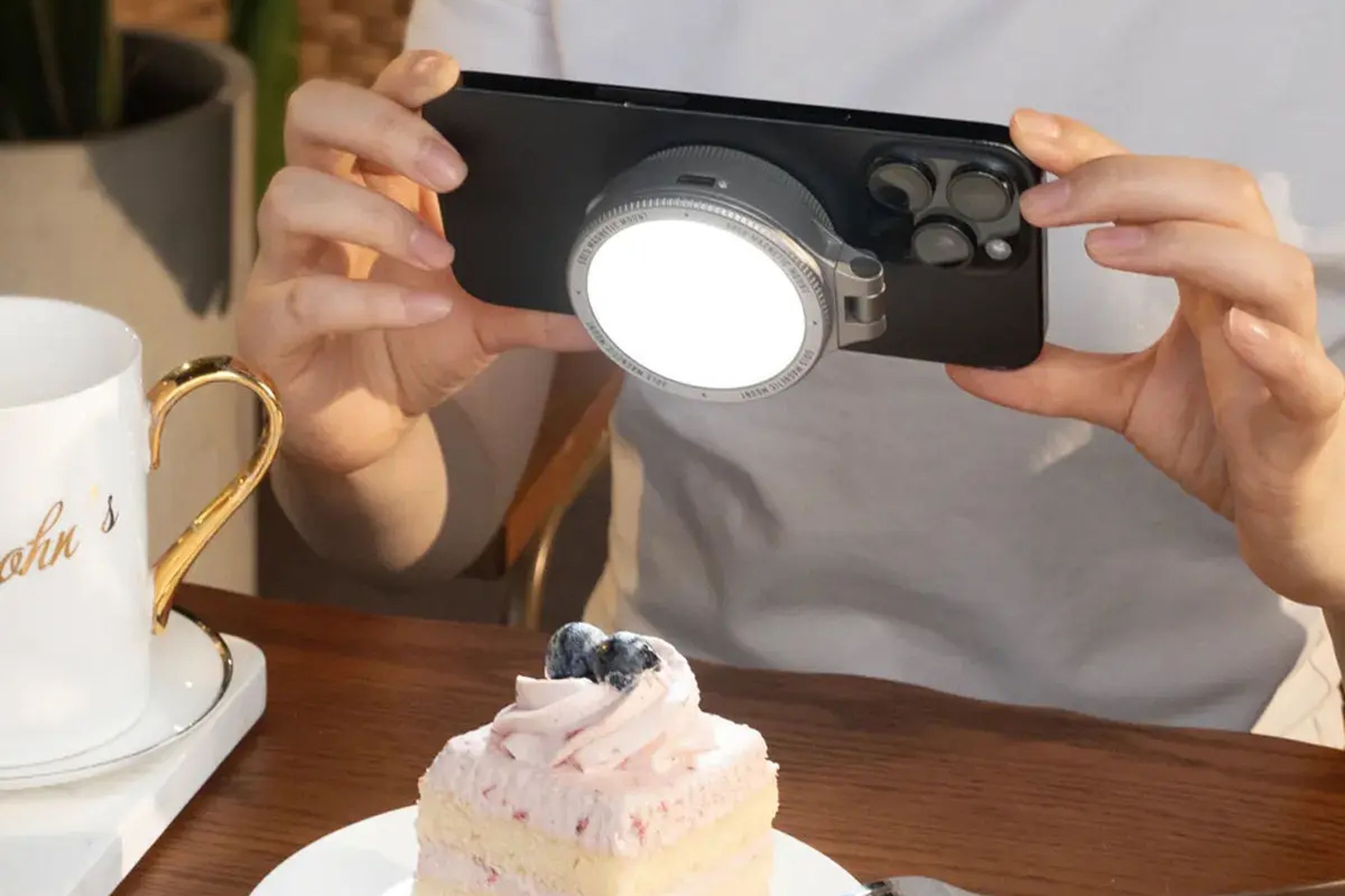 The Harlowe Sol 5 Bi-Color Mobile Light for MagSafe attached to the back of an iPhone photographing a slice of cake.