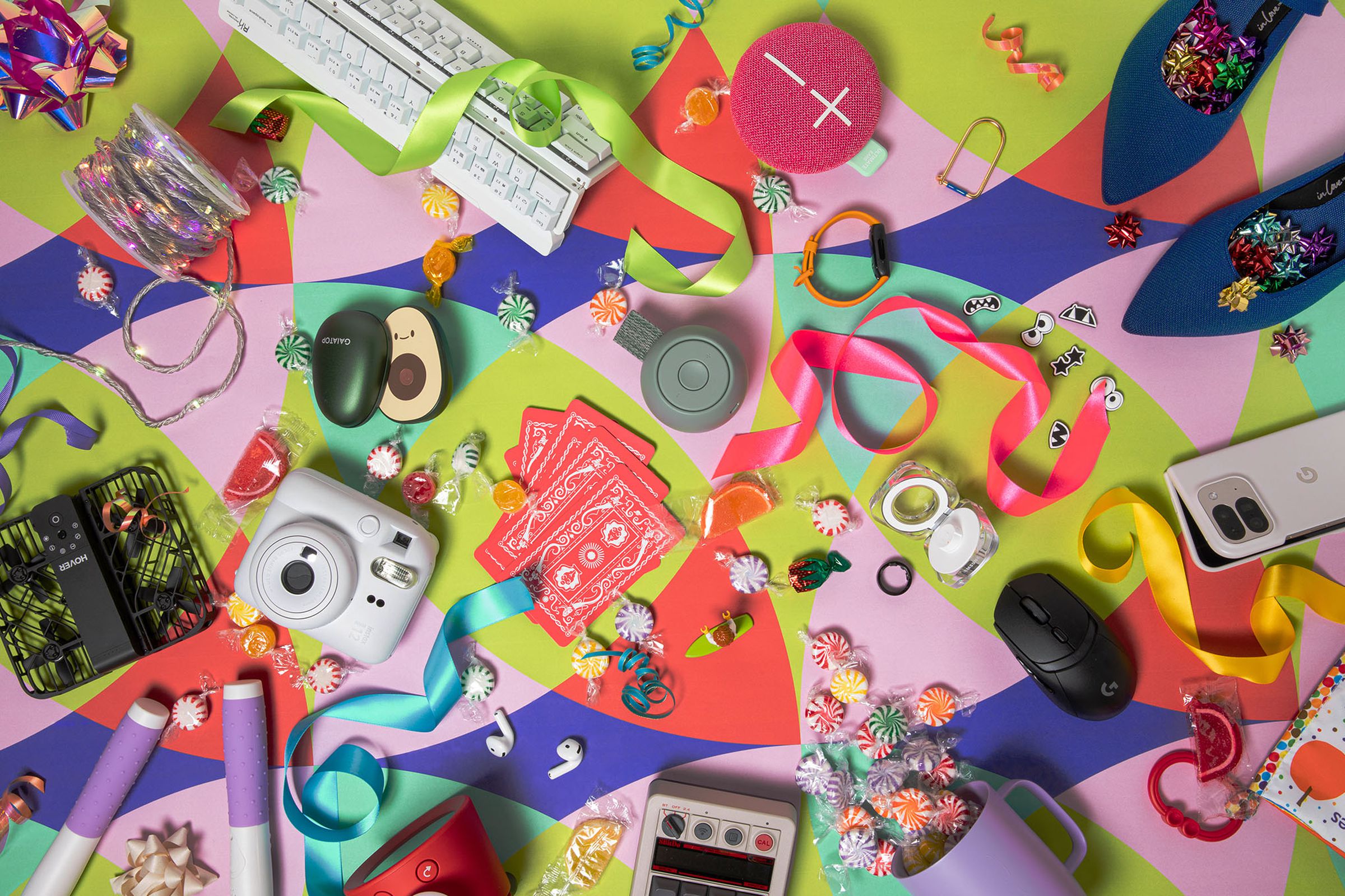 Photograph of brightly colored gifts scattered on a graphic background of vibrant patterned paper.