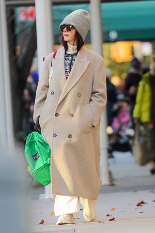 Anne Hathaway wearing a coat and beanie