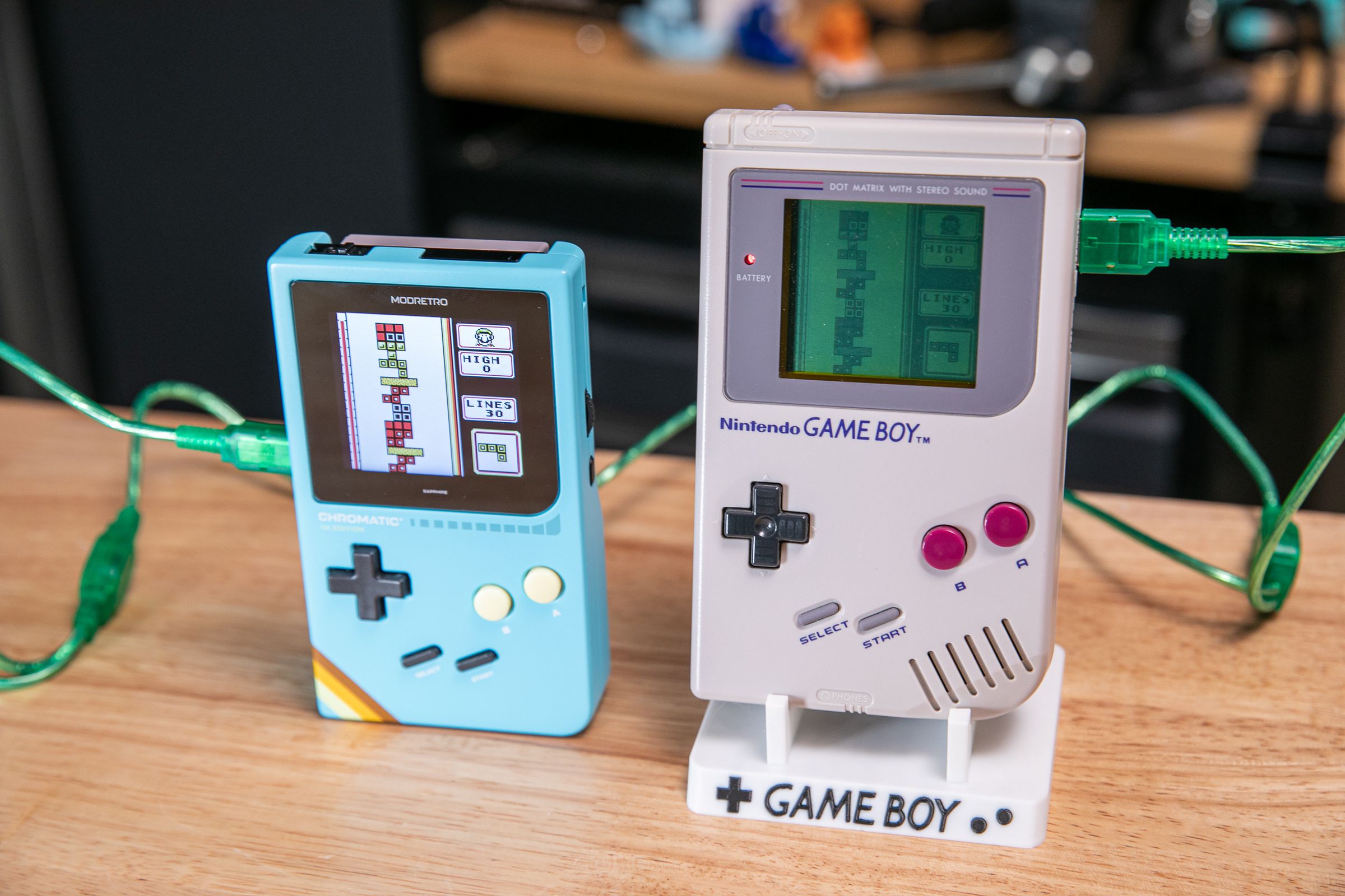 A link cable connecting an original 1989 Game Boy and a 2024 Chromatic, both playing the same original copy of Tetris for Game Boy.