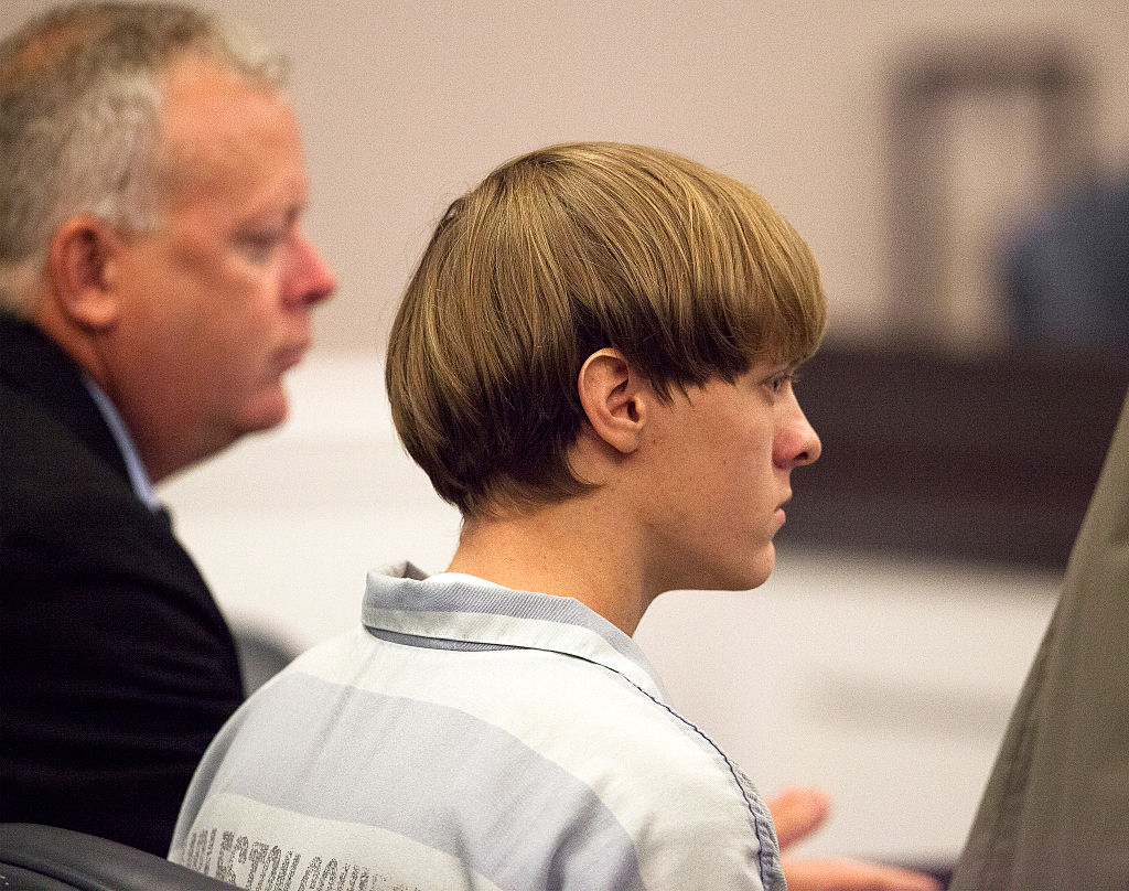 Dylann Roof (R), the 21-year-old man charged with murdering nine worshippers at a historic black church in Charleston last month, is helped to his chair by chief public defender Ashley Pennington during a hearing at the Judicial Center in Charleston