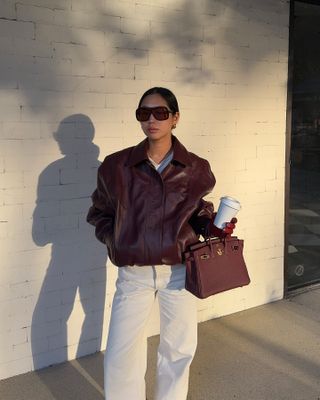 Aimee Song in a burgundy leather bomber jacket and matching Hermés bag.