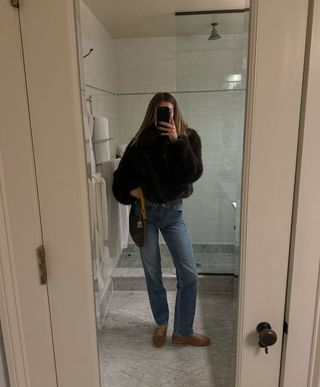 Woman wearing faux fur jacket jeans and sneakers.