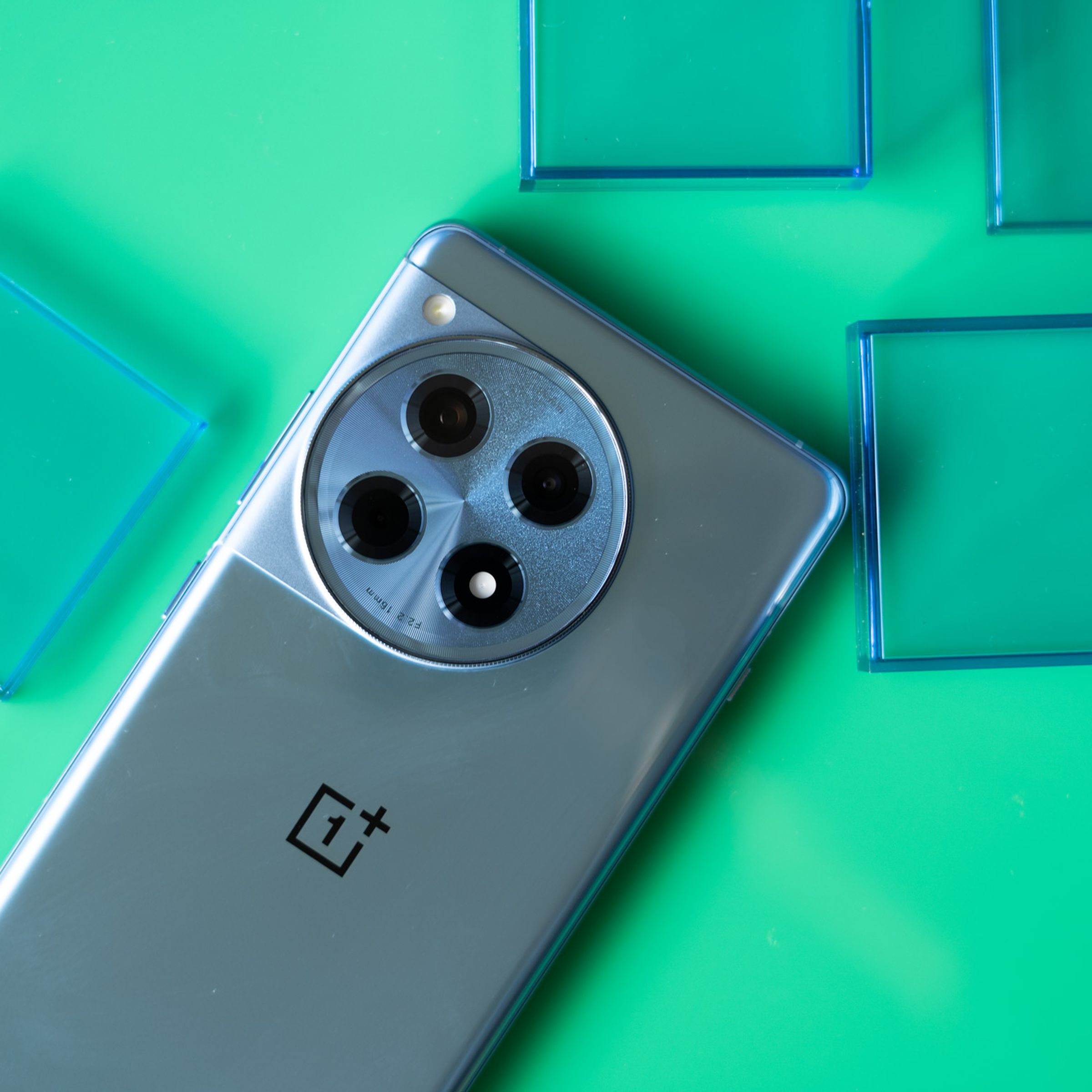 OnePlus 12R on a green background with blue translucent squares.