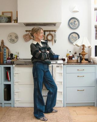 Lucy Williams in blue kitchen in striped rugby shirt and wide-leg jeans