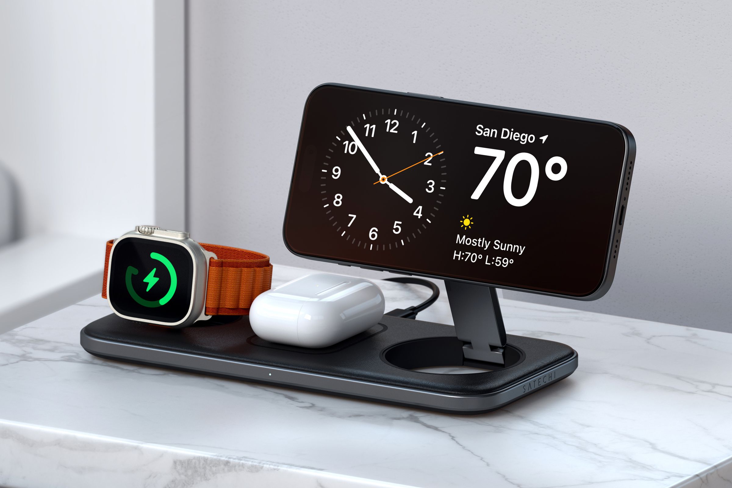 The Satechi Qi2 Trio Wireless Charging Pad on a marble table with an Apple Watch, AirPods, and iPhone charging.