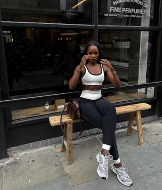 Coco wears a white sports bra, black leggings, gray new balance sneakers, and a burgundy saint laurent bag.