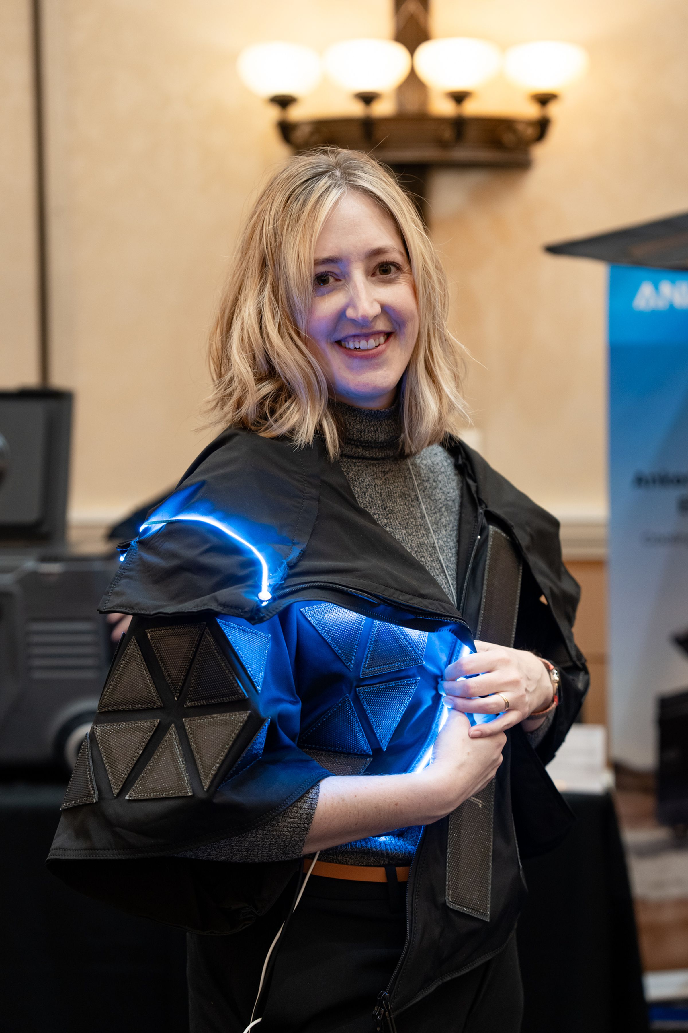 A person wearing a cloak with built-in solar panels for charging devices.